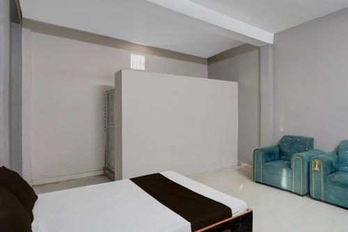a bedroom with a bed and two blue chairs at Hotel O Raj Palace in Bāra Banki
