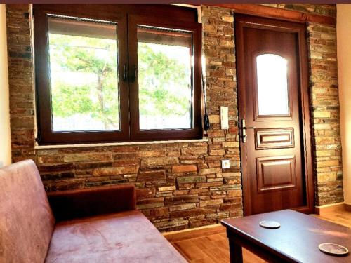a living room with a couch and a brick wall at Petroula Suites Pozar in Kato Loutraki