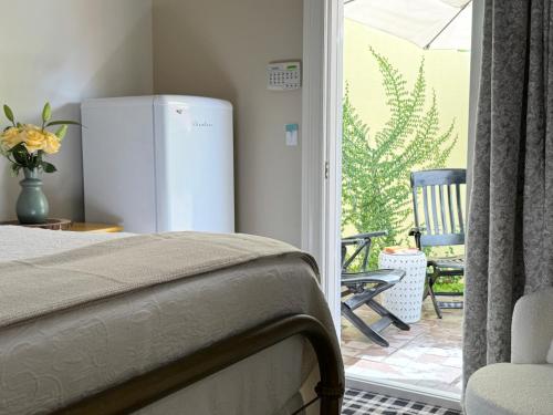 a bedroom with a refrigerator and a patio with a chair at The Rivery Retreat, Choose from Luxury Guesthouse Cabin OR Poolside Suite in Lake Austin Hill Country in Austin