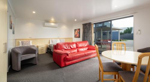 a living room with a red couch and a table at Grove Park Motor Lodge in Blenheim