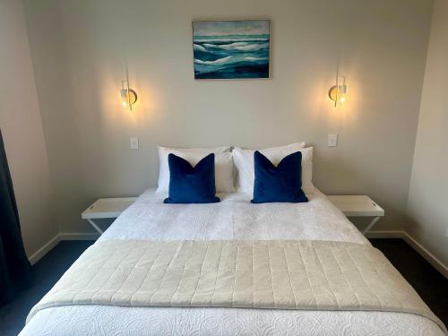 una camera da letto con un letto bianco con due cuscini blu di Kilda Cottage - Close to beach a Dunedin