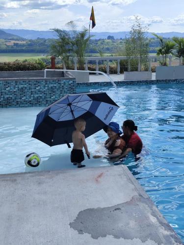 two women and a child in a swimming pool with an umbrella at Finca Maratón Alto in Calarcá