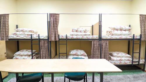 a room with bunk beds with a table and chairs at Sun Hostel in Almaty