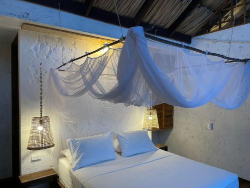 a bed with two white pillows and a blue net at Haku hotel in Palomino
