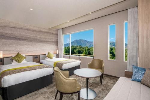 a hotel room with two beds and a table at KAMENOI HOTEL Aso in Aso
