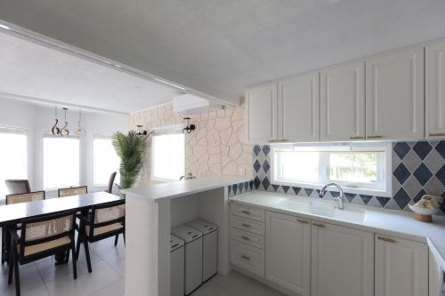 Una cocina con gabinetes blancos y una mesa de comedor. en 軽井沢の森に佇む英国様式白の宮殿 薪ストーブある5ldk ポーラーリゾート軽井沢ミューズ, en Naganohara