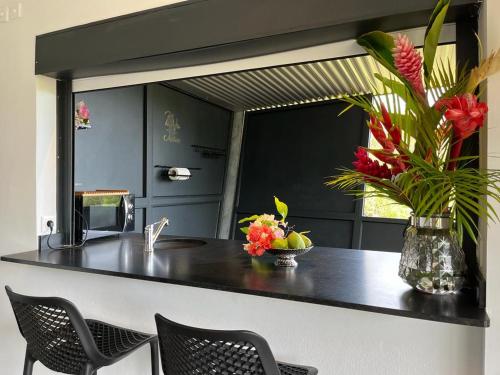 a kitchen with a counter with chairs and a vase of flowers at STUDIO O'KALM in Le Gosier