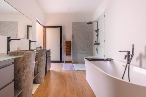 a bathroom with a large tub and a sink at Black Pool Situé à SANUR 4BR in Sanur