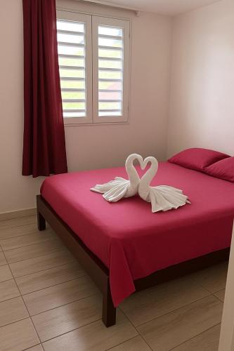 Dos cisnes formando un corazón en una cama roja en Villa bel azur, en La Trinité