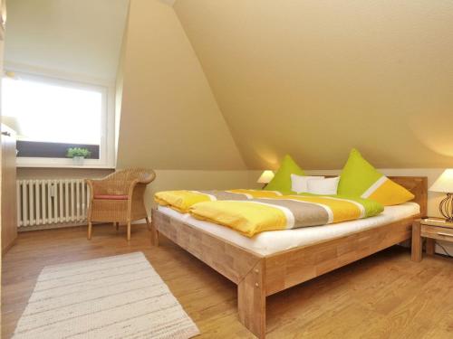 une chambre avec un lit avec des oreillers jaunes et verts dans l'établissement Süderhof Apartment 1, à Keitum