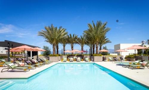 a pool with chairs and umbrellas and palm trees at Noho Alexan Modern 2bed Duo with FREE Parking in Garnsey