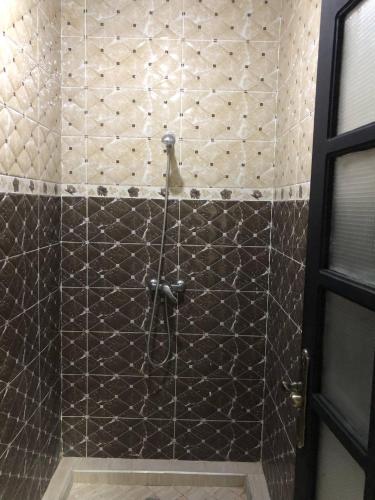 a shower with a black and white tiled wall at Villa Shahinaz 4 chambres, piscine & vue forêt in Essaouira