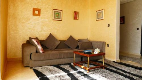 a living room with a couch and a table at Villa Shahinaz 4 chambres, piscine & vue forêt in Essaouira