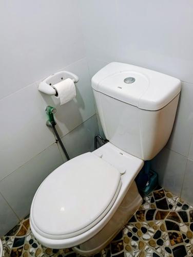 a white toilet in a bathroom with a roll of toilet paper at Zia Homestay in Burgos