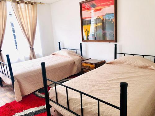 キトにあるApartamento Grande para tu comodidad-Large apartment for your comfortのベッドが2つあり、壁に絵が飾られた寝室