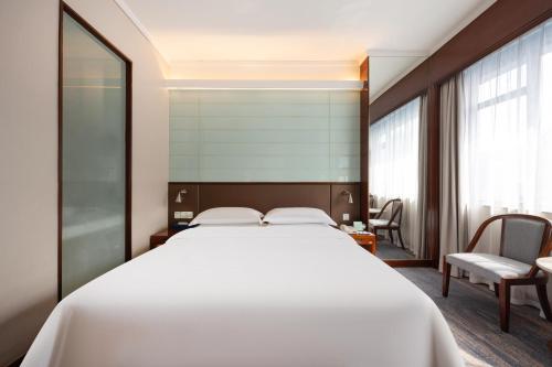 a bedroom with a large white bed and a chair at Ocean Hotel Guangzhou - Free Shuttle Bus to Canton Fair, Tao Jin railway station in Guangzhou