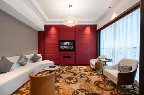 a living room with a white couch and a red wall at Ocean Hotel Guangzhou - Free Shuttle Bus to Canton Fair, Tao Jin railway station in Guangzhou