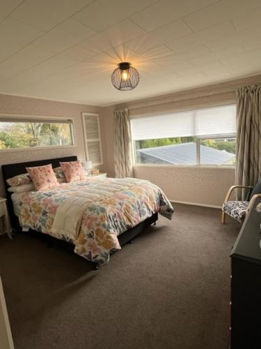 a bedroom with a bed and two windows at Boutique on Russel in Invercargill