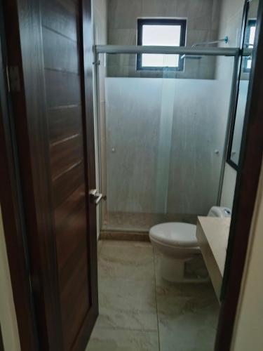a bathroom with a toilet and a glass shower door at Hacienda Valbuena Antorcha area in León