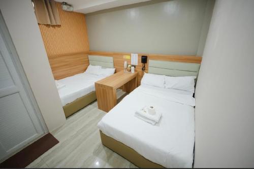 a small room with two beds and a desk at Casa Familia Hotel in Aurora