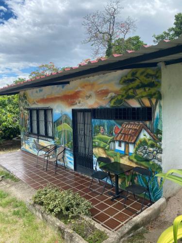 a mural on the side of a house with chairs and a table at Hotel Campestre Las Margaritas Rivera in Rivera