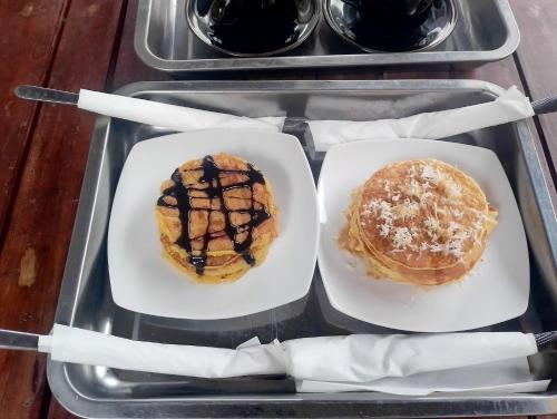 a tray with two plates of pancakes and syrup at Lentera Lombok in Tetebatu