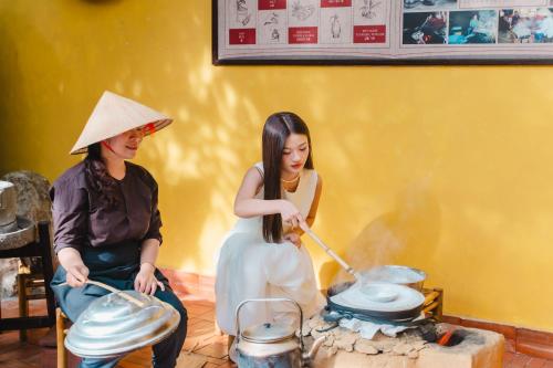 two women are playing pots and pans on a table at The Signature Hoi An in Hoi An