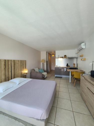 a bedroom with a large bed and a kitchen at Studio à la plage in Le Gosier