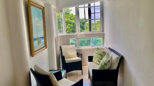a living room with two chairs and a couch and two windows at A Few Steps to Malecon and Sunny Beaches in Las Flores