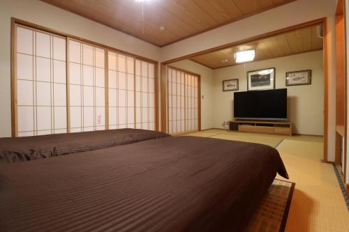 a bedroom with a bed and a flat screen tv at 日田ホステル　Hita Hostel in Hita