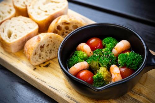 a bowl of vegetables on a cutting board with bread at ITOSHIMA SDGs Village Chikyu MIRAI -海の大パノラマ-全室オーシャンビューのドームテント in Itoshima