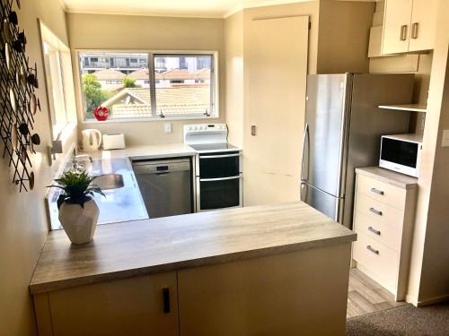 a kitchen with a counter top and a refrigerator at 3 Bedroom Apartment next to Blake Park in Mount Maunganui