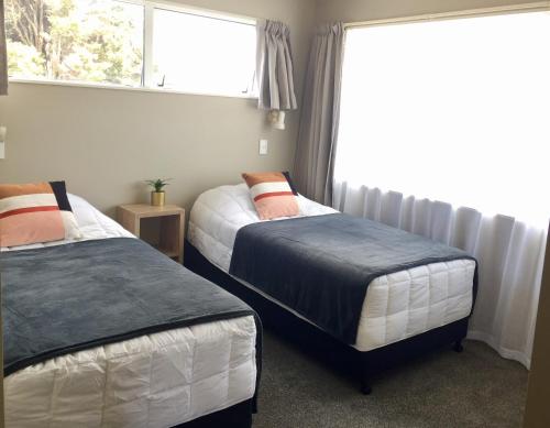 two beds in a room with a window at 3 Bedroom Apartment next to Blake Park in Mount Maunganui
