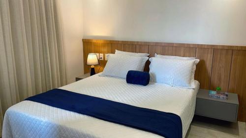 a bedroom with a large bed with white and blue sheets at Flat sofisticado na Praia do Cabo Branco 4 pessoas in Tambaú