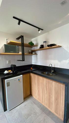 a kitchen with a sink and a refrigerator at Flat sofisticado na Praia do Cabo Branco 4 pessoas in Tambaú