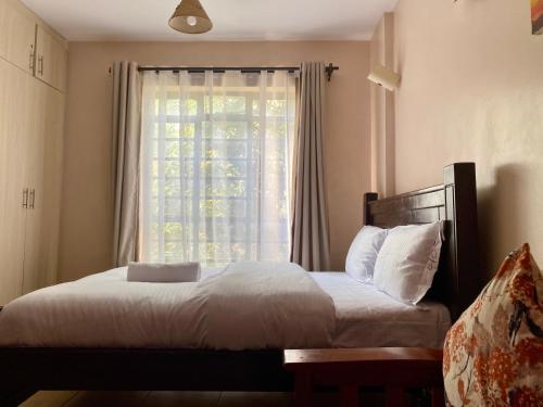 a bedroom with a bed and a window with curtains at Furnished Studio Apartment in Nairobi West in Nairobi