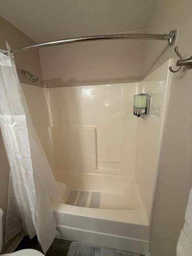 a small bathroom with a shower with a toilet at Fun & Comfort for 8 in Roger! King & Arcade Games in Rogers