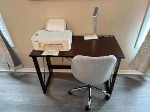 a desk with a printer and a chair on it at Fun & Comfort for 8 in Roger! King & Arcade Games in Rogers