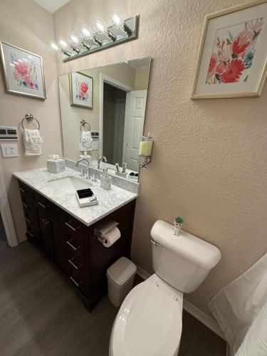 a bathroom with a toilet and a sink and a mirror at Fun & Comfort for 8 in Roger! King & Arcade Games in Rogers