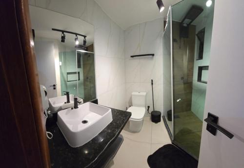 a bathroom with a sink and a shower and a toilet at Loft Prainha in Arraial do Cabo