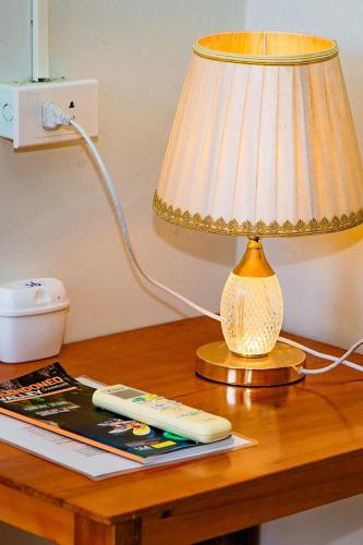a lamp sitting on a table with a remote control at Phong Nha Cherish Homestay in Bố Trạch
