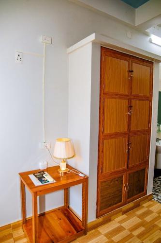 a table with a lamp next to a wooden door at Phong Nha Cherish Homestay in Bố Trạch