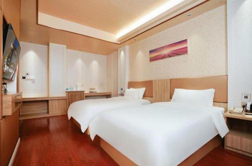 two beds in a hotel room with white sheets at Quanzhou Binhai Hotel in Quanzhou