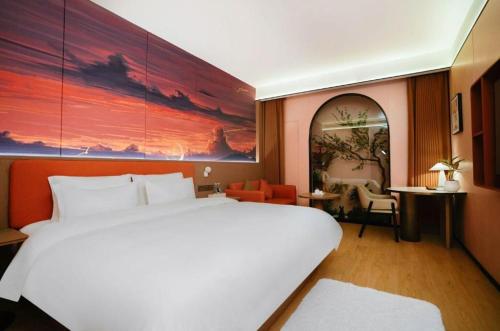 a bedroom with a large white bed and a large painting at Quanzhou Binhai Hotel in Quanzhou