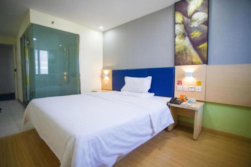 a bedroom with a large white bed and a table at 7 Days Inn Jinan Changqing Jingshi West Road Center in Jinan
