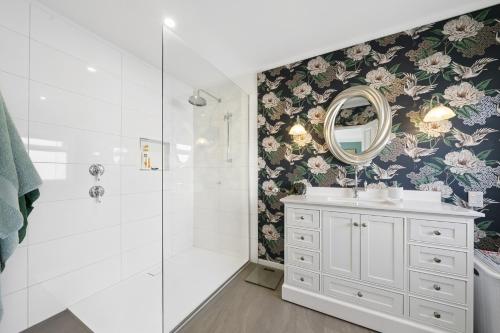 a bathroom with a shower and a sink and a mirror at Fishermans Cottage - Waikanae Beach in Waikanae