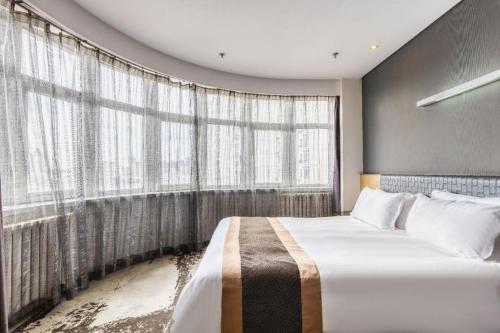 a bedroom with a large bed and a large window at Harbin Splendent Hotel in Harbin
