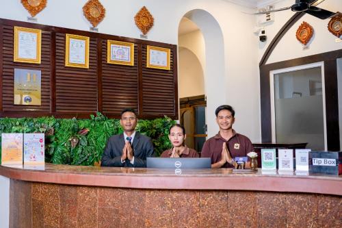 a group of three people sitting at a counter with a laptop at Sokchea Angkor Hotel in Siem Reap