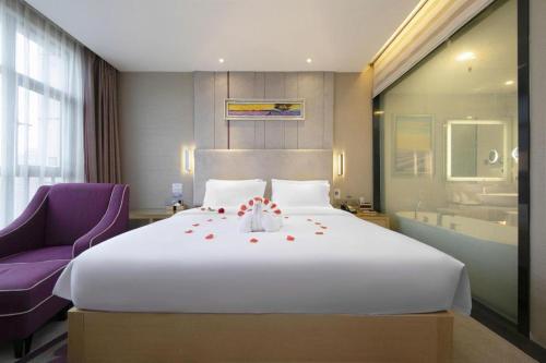 a bedroom with a large white bed with a purple chair at Lavande Hotel Yichang Railway East Station Branch in Yichang