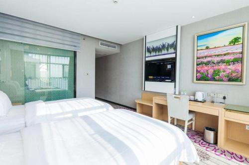 a bedroom with a large white bed and a desk at Lavande Hotel Yichang Railway East Station Branch in Yichang